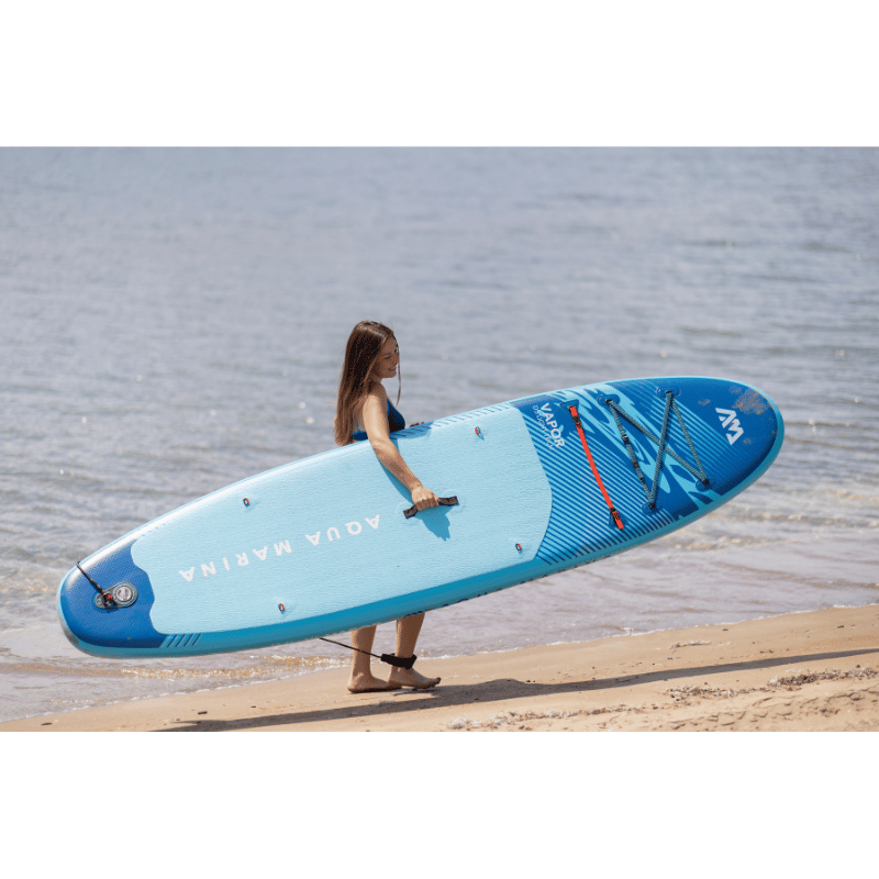 A Person Carrying a Aqua Marina 10'4" VAPOR 2026 Inflatable Paddle Board 