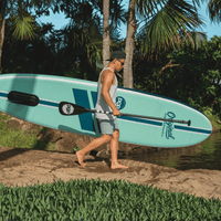 Thumbnail for A man carrying a POP Yacht Hopper 11' Inflatable Touring Paddle Board SUP with Cooler Mount – Mint/Teak/Blue